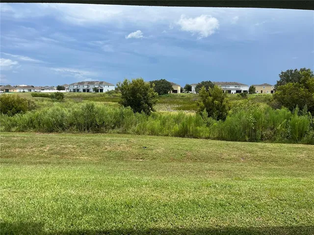 a view of a field with an ocean and trees