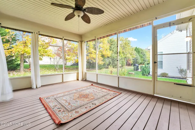 a view of an empty room with wooden floor and windows