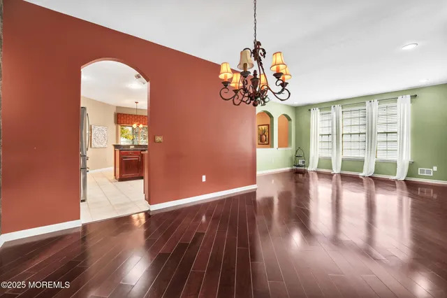 a view of a room with wooden floor chandelier and windows