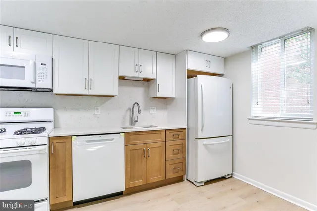 a kitchen with white cabinets white stainless steel appliances and sink