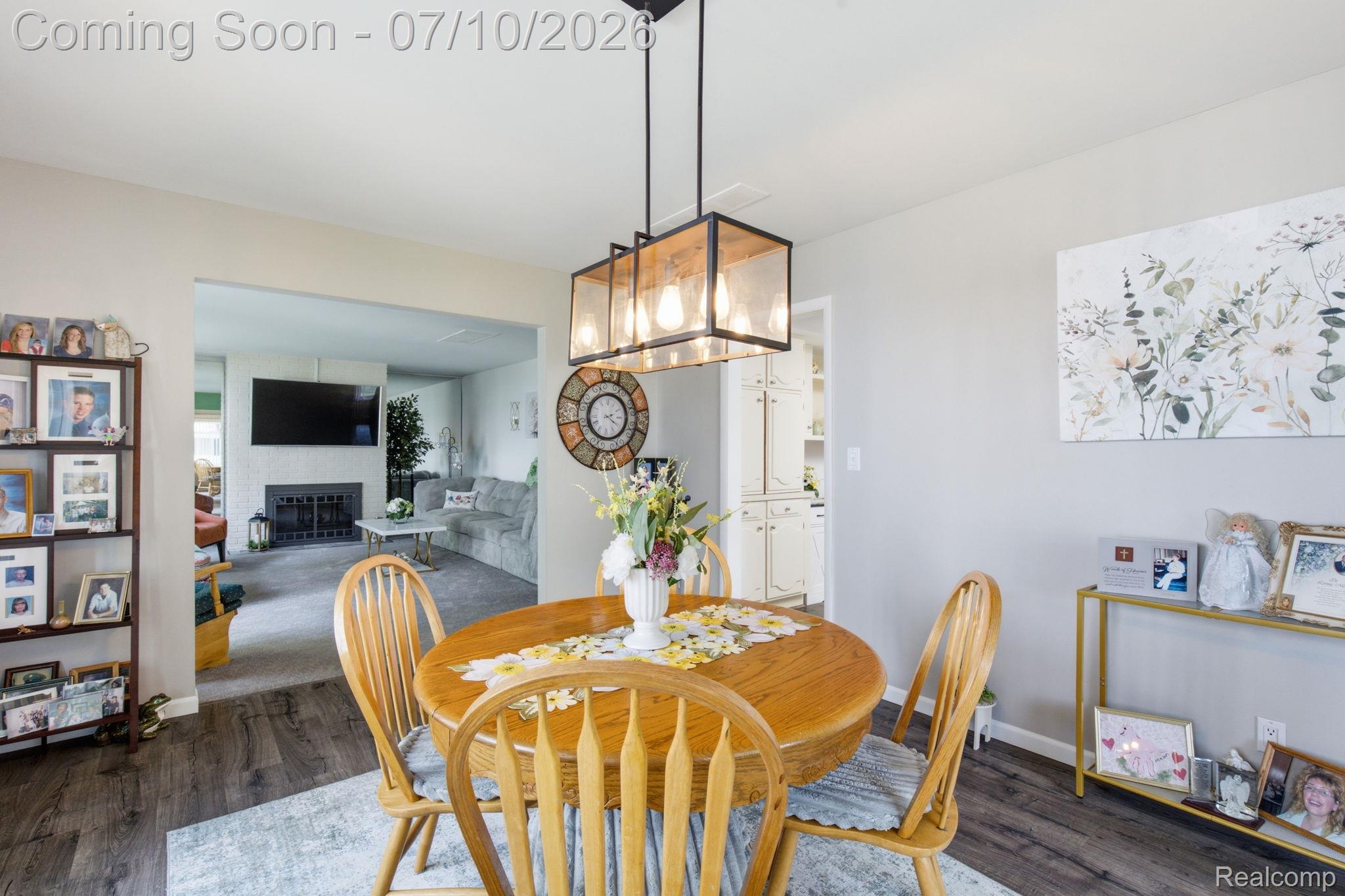 1501 River Road, Unit 301 St. Clair, MI 48079 - Photo 11 of 32 Open-concept dining area featuring wood-finish flooring, a modern multi-bulb pendant light fixture, and a pass-through to an additional room with a fireplace