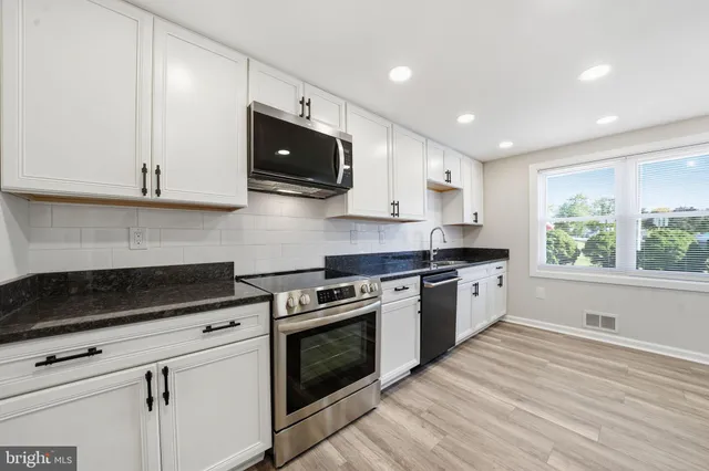a kitchen with stainless steel appliances granite countertop a stove a sink and a microwave