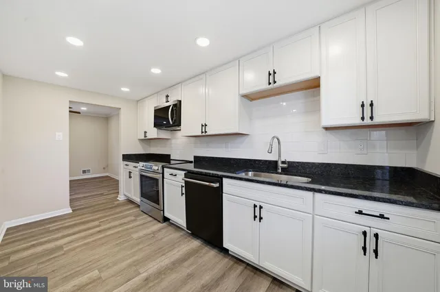 a kitchen with granite countertop white cabinets and stainless steel appliances