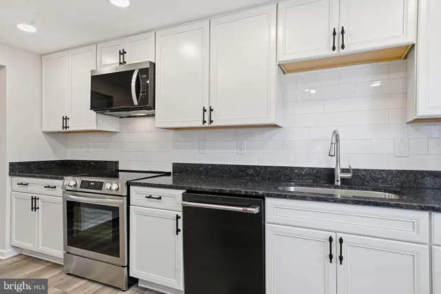 a kitchen with white cabinets and stainless steel appliances