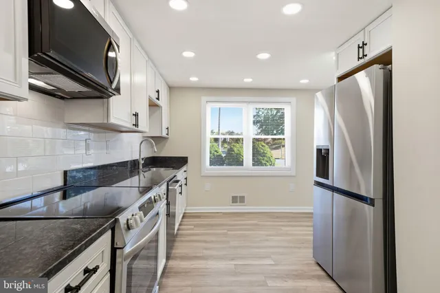 a kitchen with stainless steel appliances granite countertop a refrigerator a sink and a stove