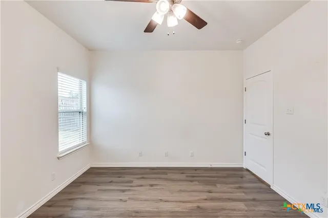 an empty room with wooden floor cabinet and windows