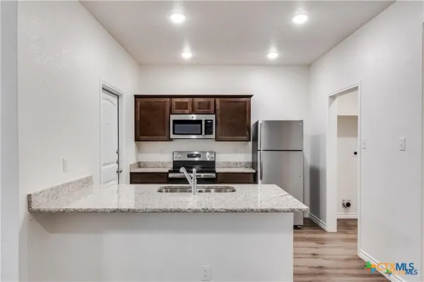 a kitchen with stainless steel appliances granite countertop a sink and a refrigerator