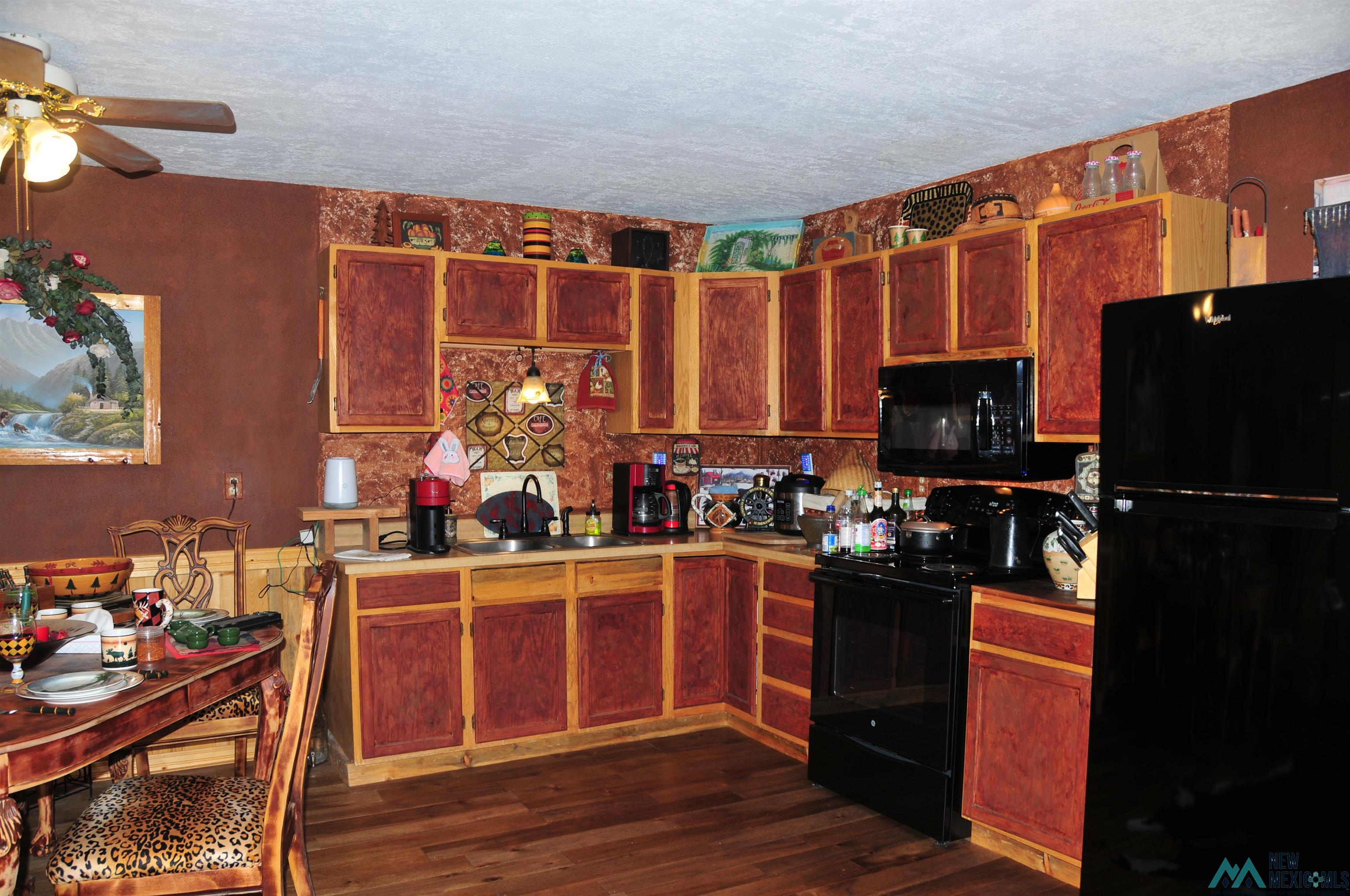 25 Bluff Road Thoreau, NM 87323 - Photo 11 of 31 Kitchen featuring wood-finish flooring, wood cabinetry, built-in microwave, black refrigerator, and a ceiling fan