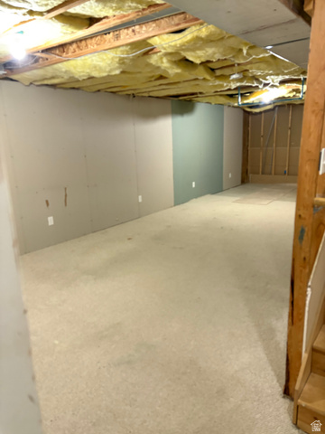 587 West 2400 South Perry, UT 84302 - Photo 37 of 46 Unfinished basement space featuring exposed ceiling joists with insulation, partial wall framing, and light-colored carpeting