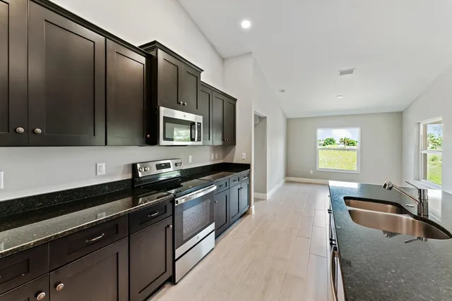 a kitchen with stainless steel appliances granite countertop a sink a stove and a microwave