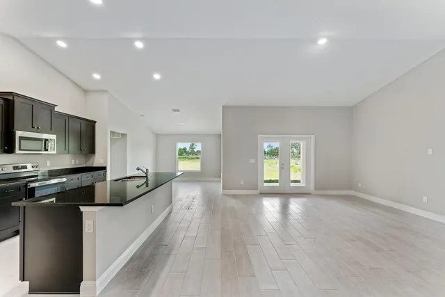 a large kitchen with stainless steel appliances a large counter top a stove a sink and a refrigerator