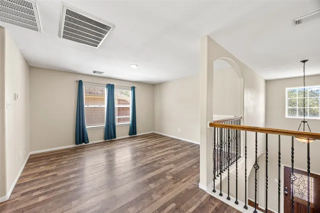 a view of an empty room with wooden floor and a window