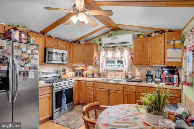 a kitchen with stainless steel appliances granite countertop a sink dishwasher a stove a refrigerator and a dining table with wooden floor