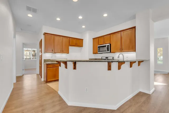 a kitchen with granite countertop a sink stove and microwave