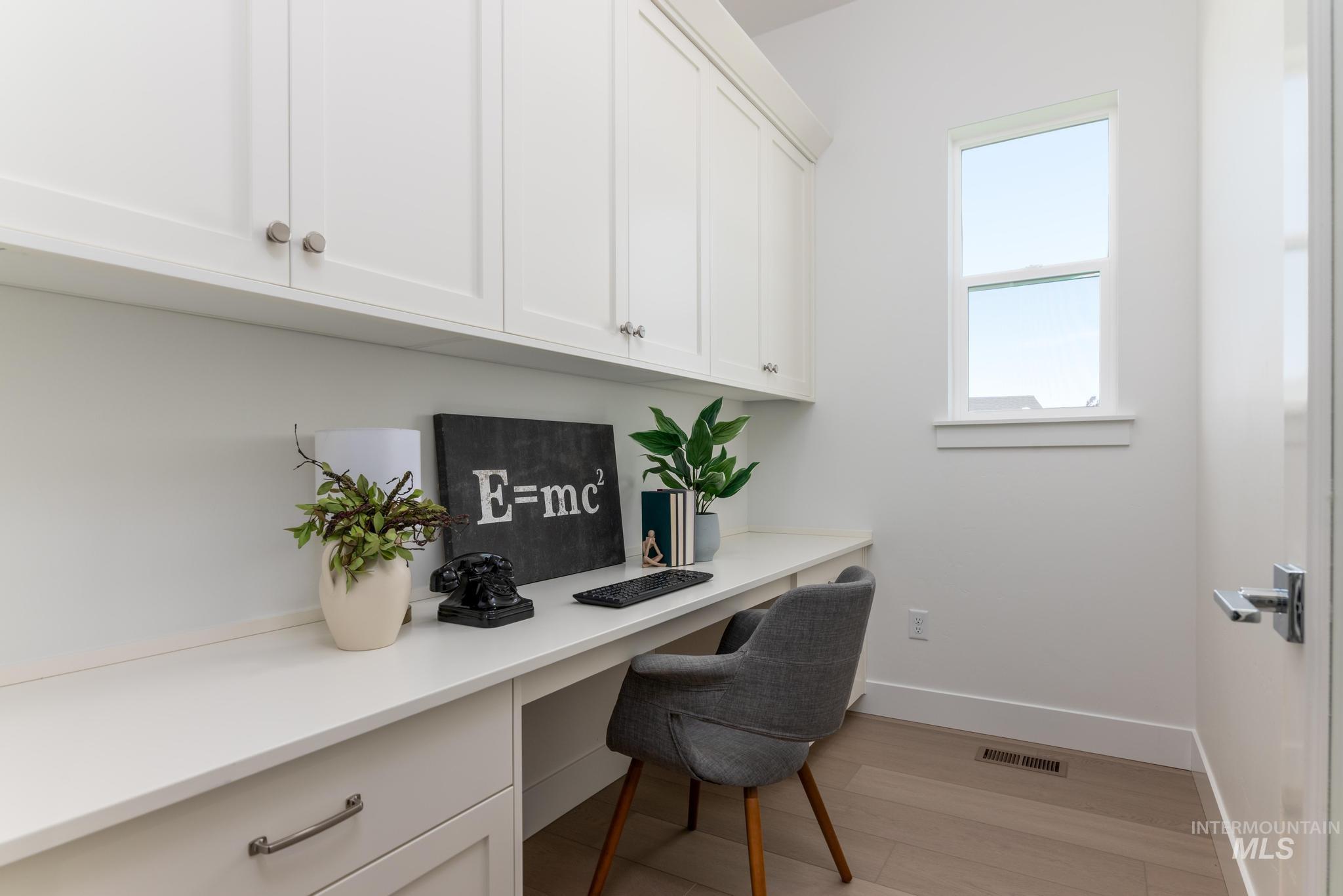 8501 South Country Wind Avenue Meridian, ID 83642 - Photo 17 of 39 Dedicated workspace featuring a built-in desk, upper cabinetry with brushed nickel hardware, and wood-finish flooring
