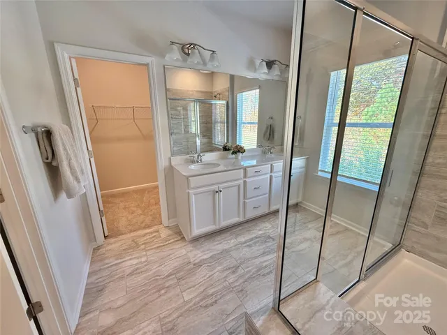 a large bathroom with a double vanity sink a large mirror and shower