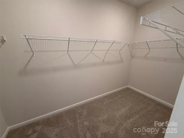 an empty room with a chandelier fan and windows