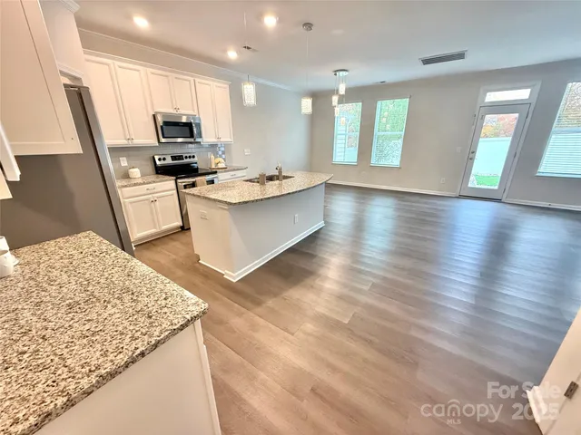 a large kitchen with stainless steel appliances kitchen island granite countertop a sink a stove a microwave a counter space and cabinets