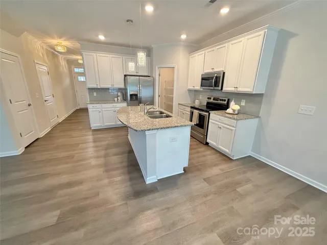 a large kitchen with stainless steel appliances granite countertop a sink stove refrigerator and cabinets