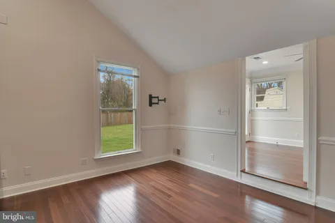 an empty room with wooden floor cabinet and windows