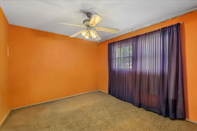 an empty room with a chandelier fan and closet
