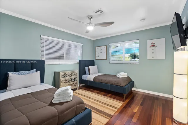 a bedroom with a bed a couch and a flat tv screen on dresser