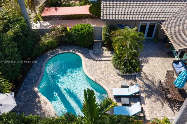 an aerial view of a swimming pool with outdoor seating and plants