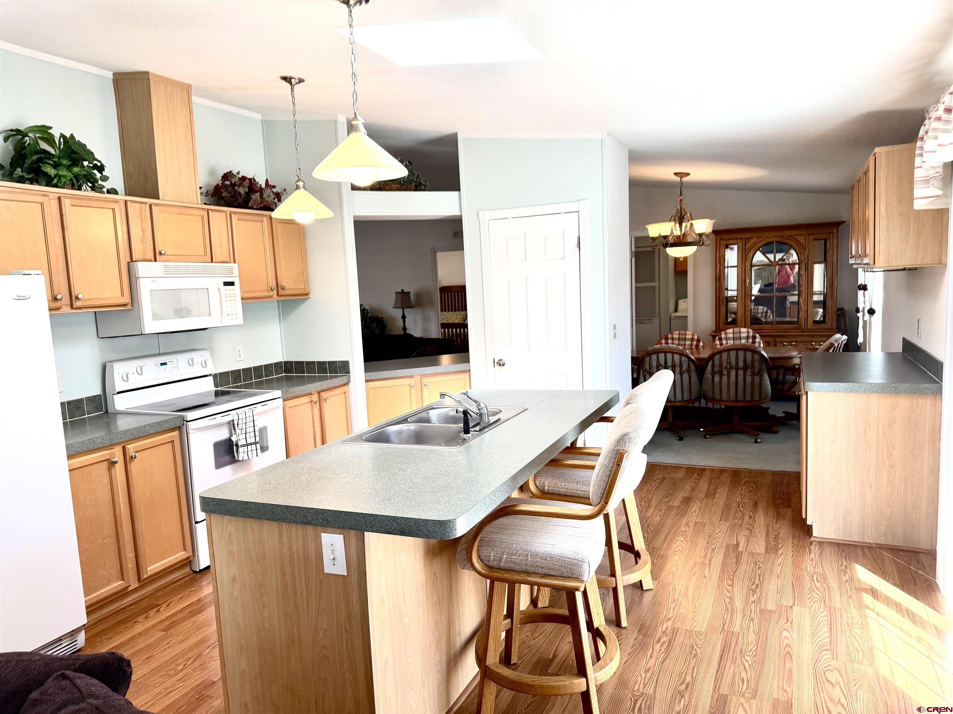 901 6530 Road, Unit 1101 Montrose, CO 81401 - Photo 28 of 45 a kitchen with stainless steel appliances kitchen island granite countertop a table chairs in it and wooden floors
