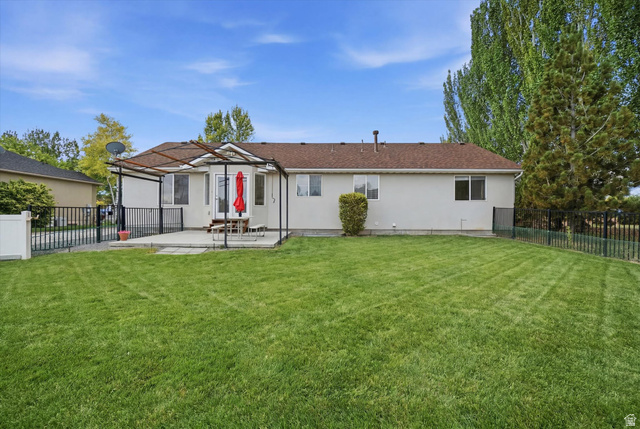 791 East Saddle Road Grantsville, UT 84029 - Photo 40 of 46 Expansive green lawn with a concrete patio featuring a pergola structure