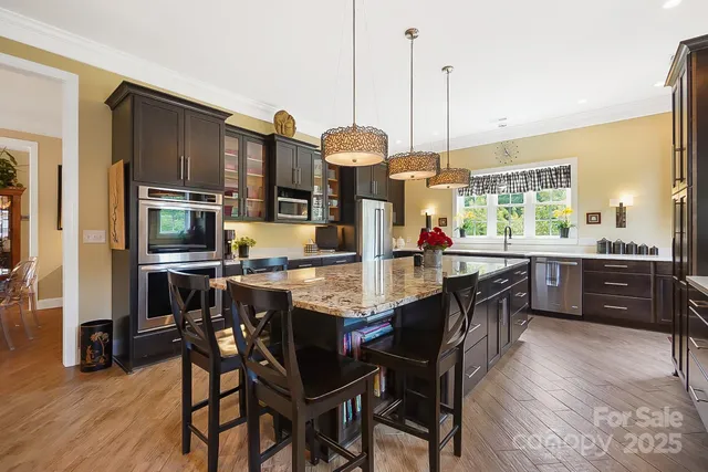 a kitchen with stainless steel appliances granite countertop a stove a sink dishwasher a dining table and chairs with wooden floor