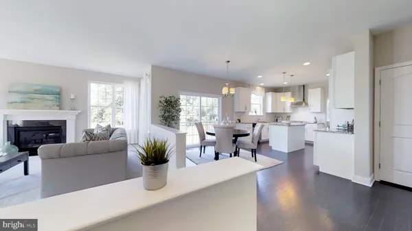 a living room with furniture a fireplace a potted plant and a kitchen view
