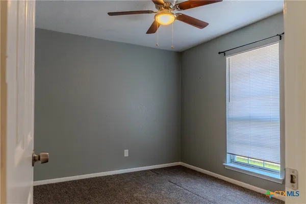 an empty room with ceiling fan and window