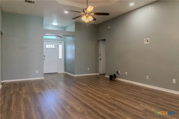 an empty room with wooden floor and windows