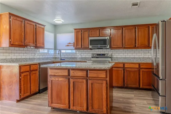 a kitchen with granite countertop wooden cabinets a stove top oven a sink and dishwasher
