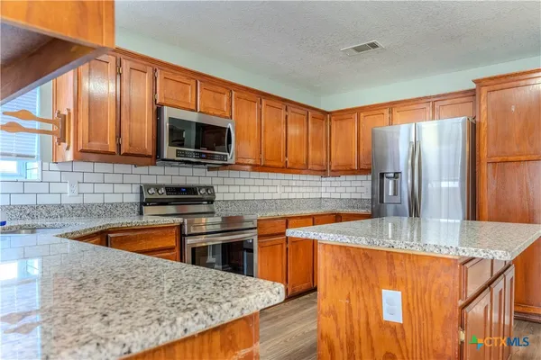 a kitchen with stainless steel appliances granite countertop a sink stove and refrigerator