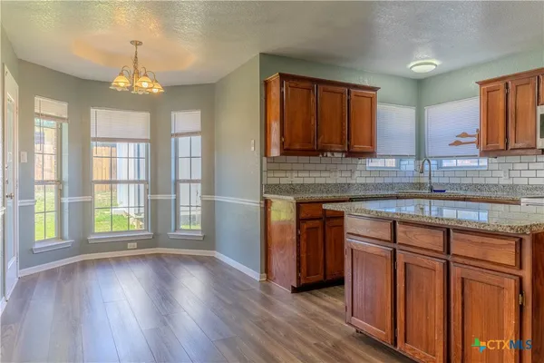 a kitchen with stainless steel appliances granite countertop wooden floors and granite counter tops