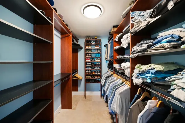 a view of walk in closet with clothes and shoes