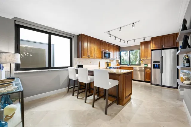 a living room with stainless steel appliances kitchen island furniture and a large window