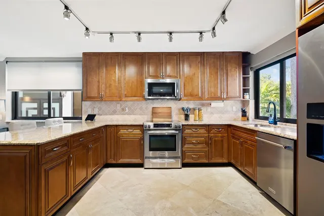 a kitchen with stainless steel appliances granite countertop a stove top oven a sink dishwasher and a microwave oven on the blue kitchen countertops