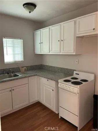 a kitchen with granite countertop white cabinets and a stove