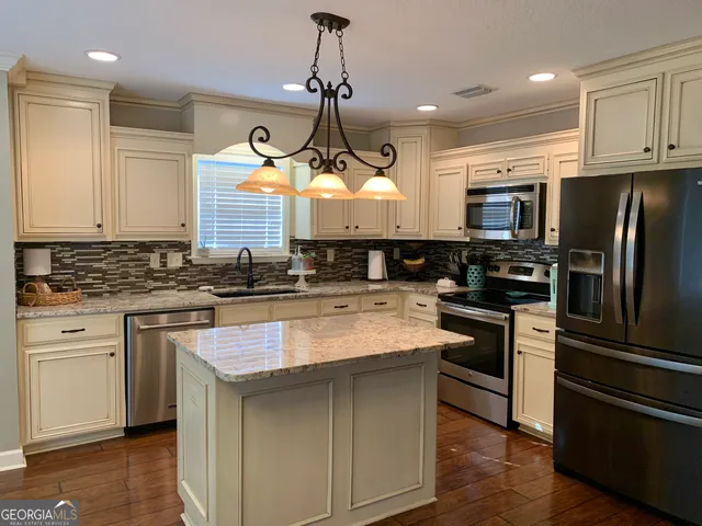 a kitchen with granite countertop white cabinets and stainless steel appliances