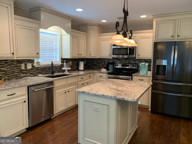 a kitchen with stainless steel appliances granite countertop a sink a stove and a refrigerator