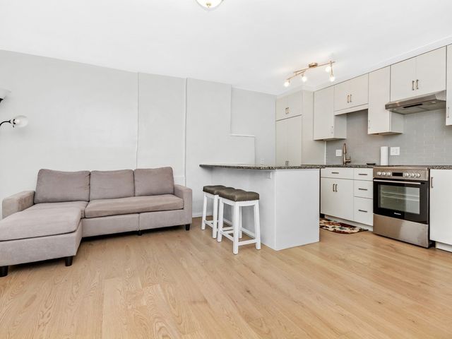 a living room with stainless steel appliances furniture and a kitchen view