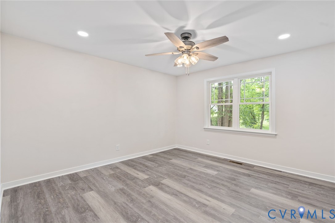14501 Hopeful Church Road Bumpass, VA 23024 - Photo 25 of 33 an empty room with wooden floor chandelier fan and windows