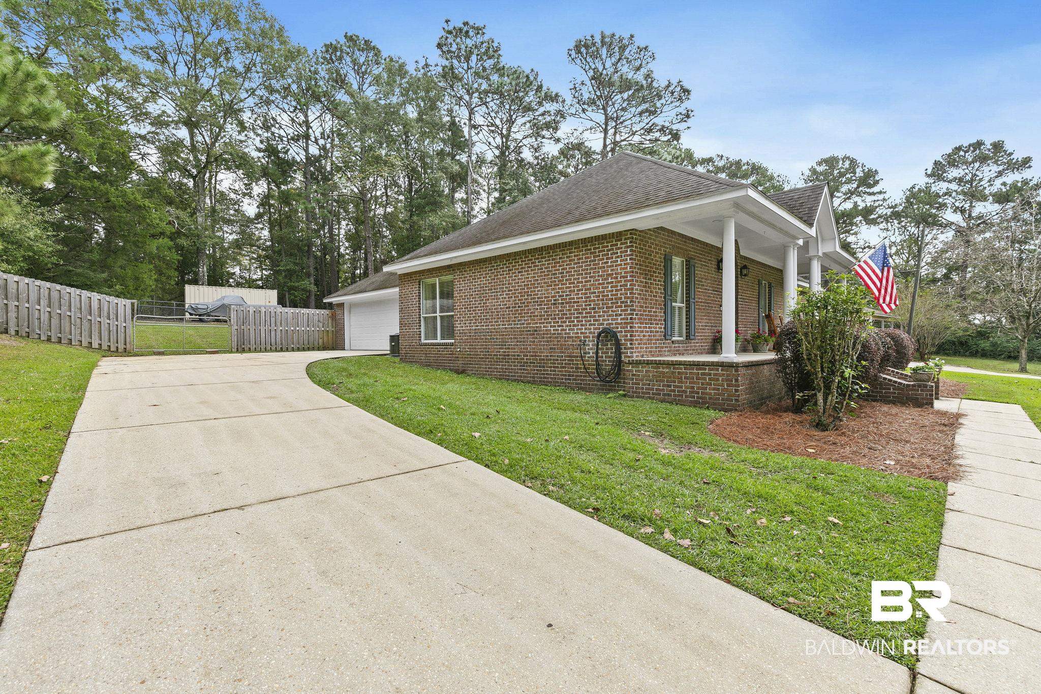 32072 Buzbee Road Daphne, AL 36527 - Photo 24 of 41 View of side of property featuring a porch, a garage, and a lawn