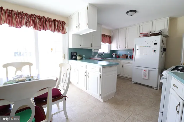 a kitchen with kitchen island a stove a sink a refrigerator and cabinets