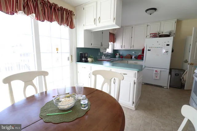 a kitchen with stainless steel appliances kitchen island granite countertop a refrigerator a stove a sink dishwasher and white cabinets with wooden floor