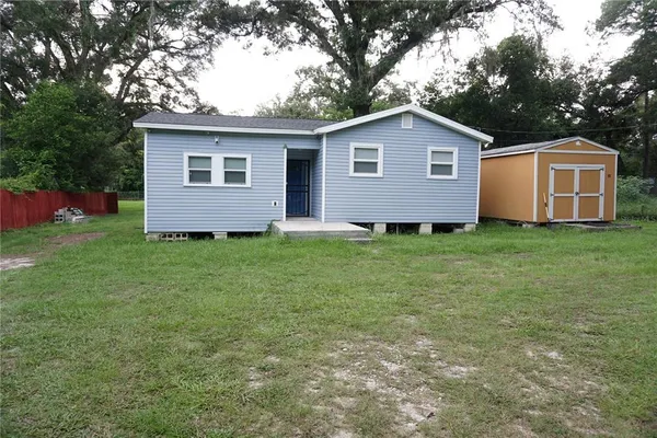 a front view of house with yard and trees in the background