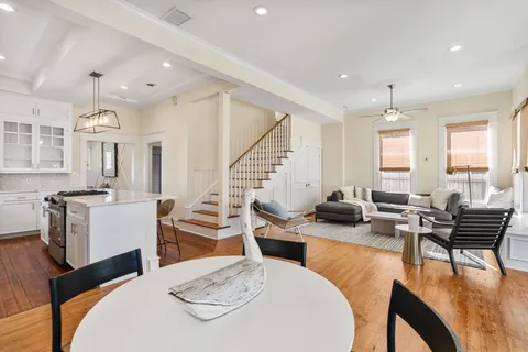 a living room with furniture kitchen view and a wooden floor