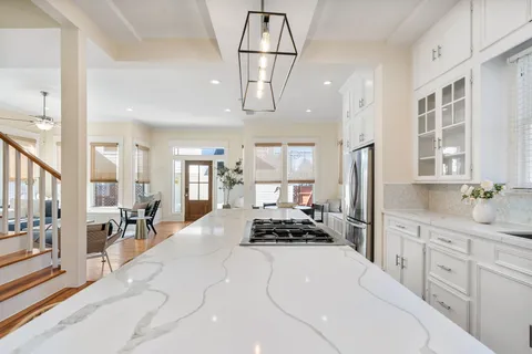 a kitchen with stainless steel appliances a stove a sink dishwasher a dining table and cabinets with wooden floor